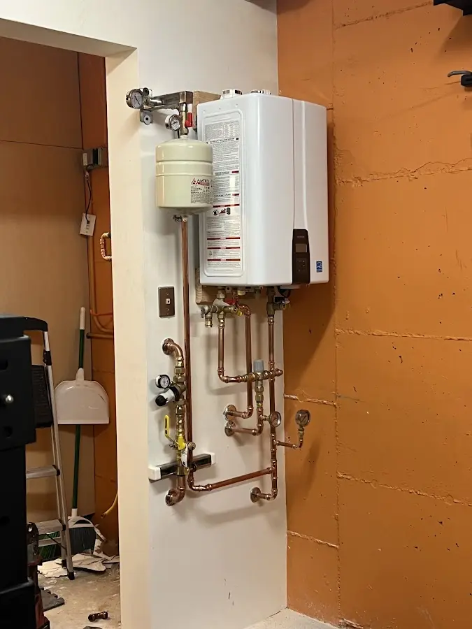 Plumbing technician inspecting water heater connections in Millington